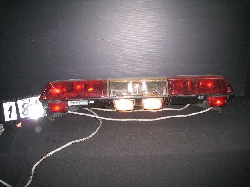 lot 184 image: Police car emergency light bar, functional with roof mounting brackets, runs off 12V, needs a couple replacement bulbs, has wiring harness but no control box. Bidder should inspect.