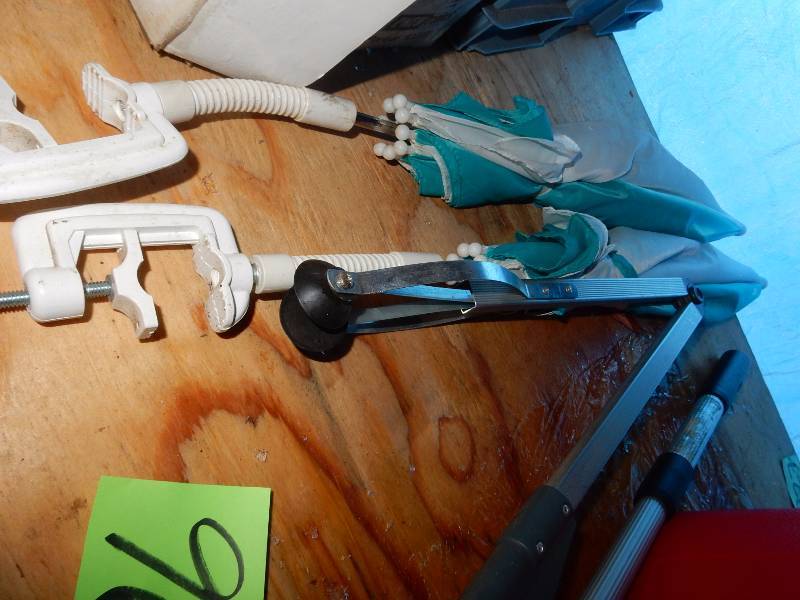 lot 96 image: Misc. items  5 gallon plastic gas can, measuring wheel, 2 clamp on umbrellas, fluoresent light fixture, pick up clamp, Fold down cart,